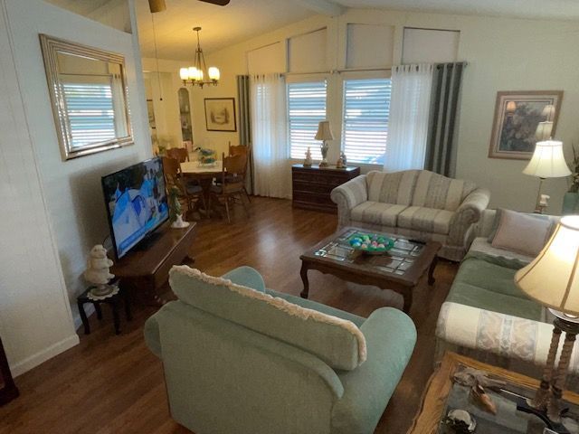 Living room with couches, TV, coffee table, and dining area visible in the background.