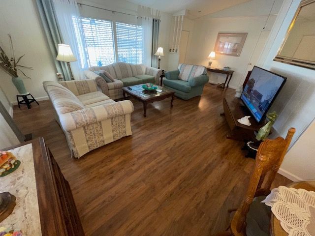 Living room with couches, chairs, TV, and wood flooring.
