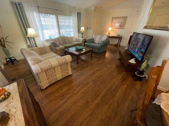 Living room with sofas, a TV, and wooden floors.