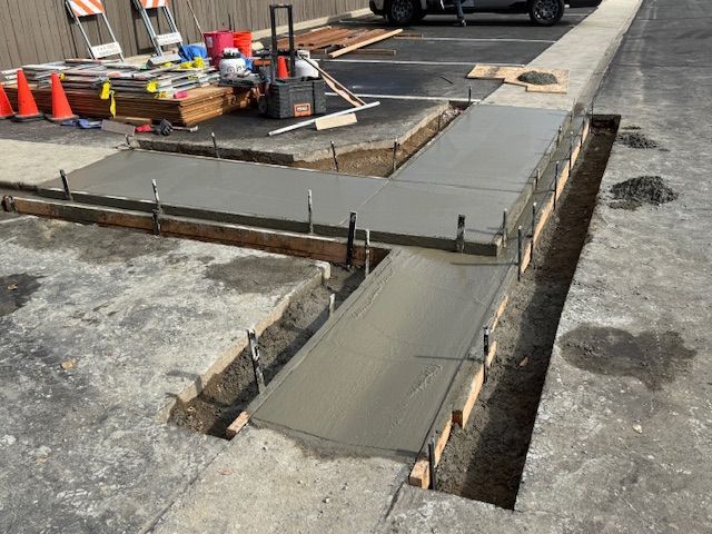Freshly poured concrete sidewalk with wooden forms and rebar. Construction site.