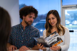 A man and a woman are looking at a brochure together.