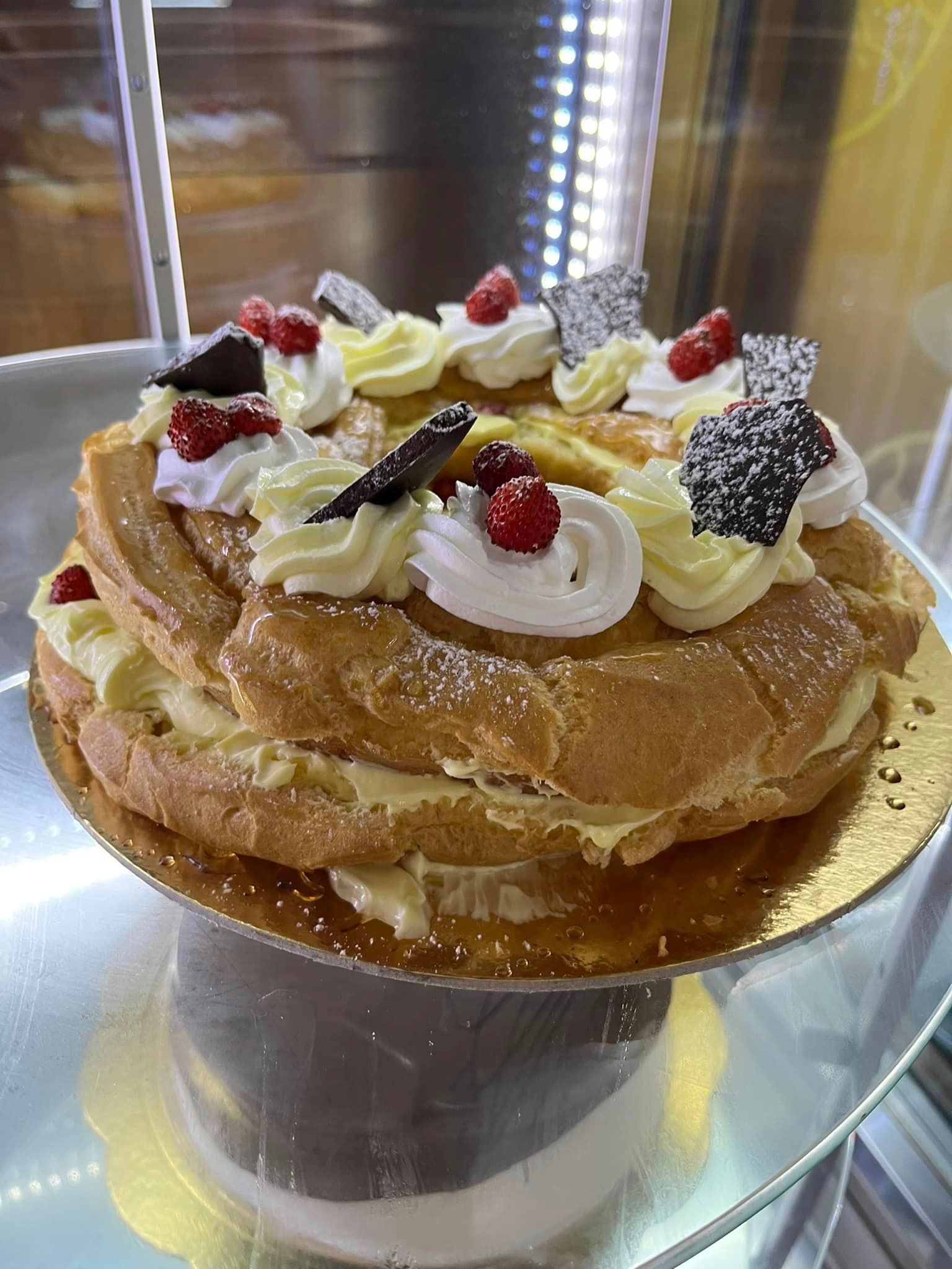 un primo piano di una torta con panna montata e frutti di bosco su un piatto.