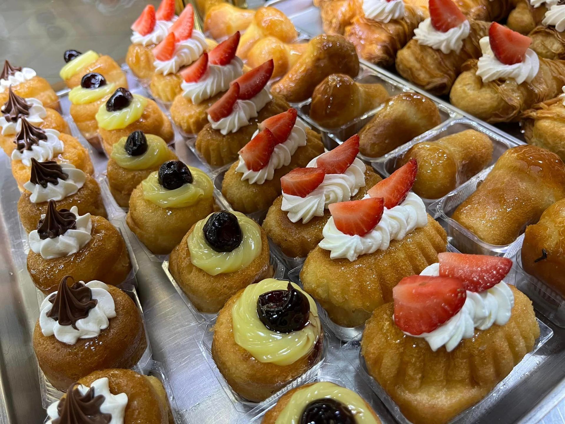 un vassoio di cupcakes con panna montata e fragole sopra.