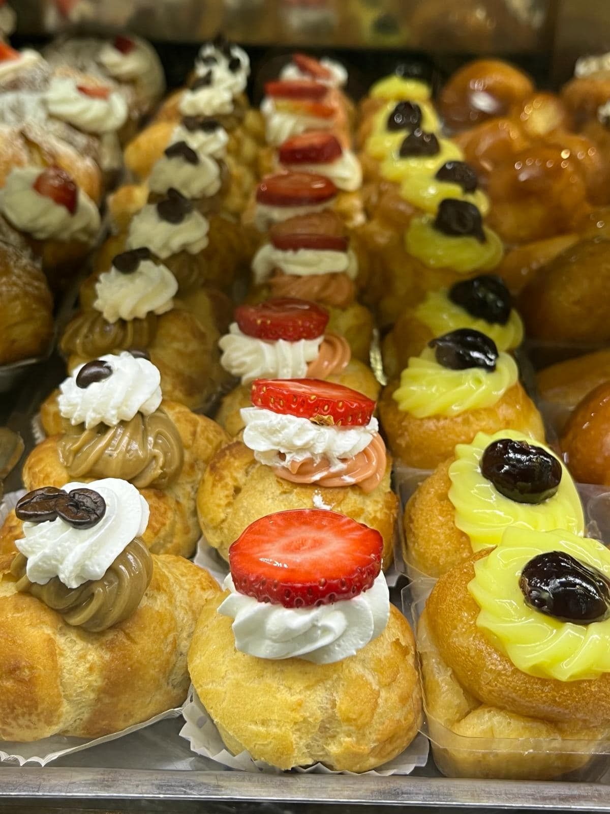 un vassoio di pasticcini con sopra fragole e panna montata.