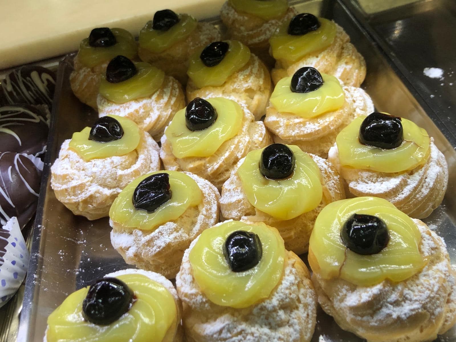 un vassoio di cupcakes con glassa gialla e amarene sopra.