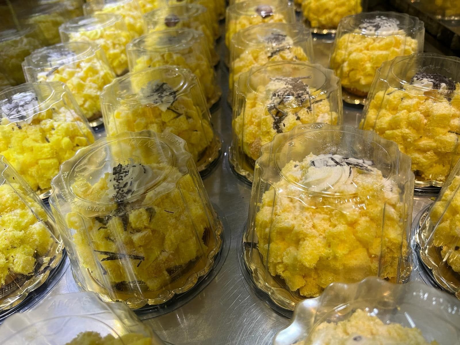 un mucchio di dolci gialli in bicchieri di plastica su un tavolo.