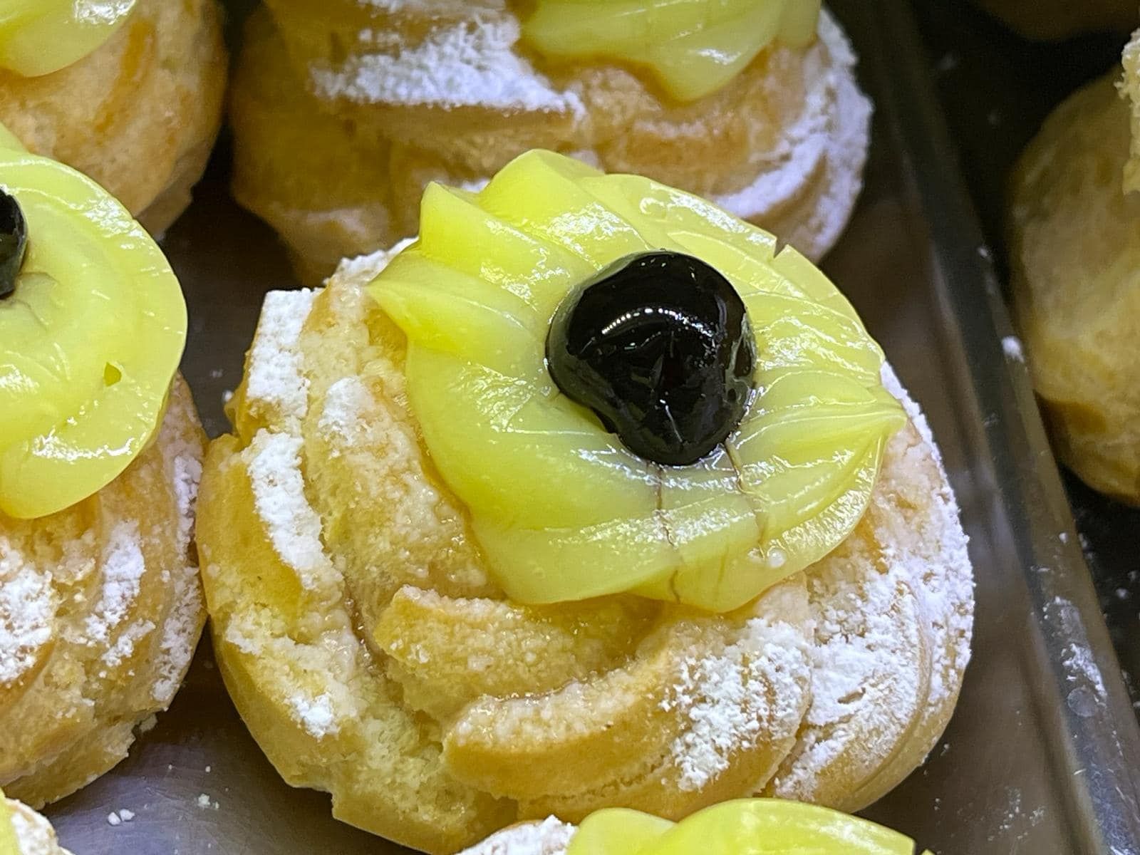 un primo piano di un dolce con glassa gialla e una ciliegina sulla torta.