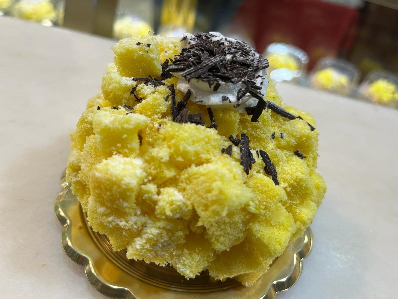 una torta gialla con panna montata e scaglie di cioccolato sopra