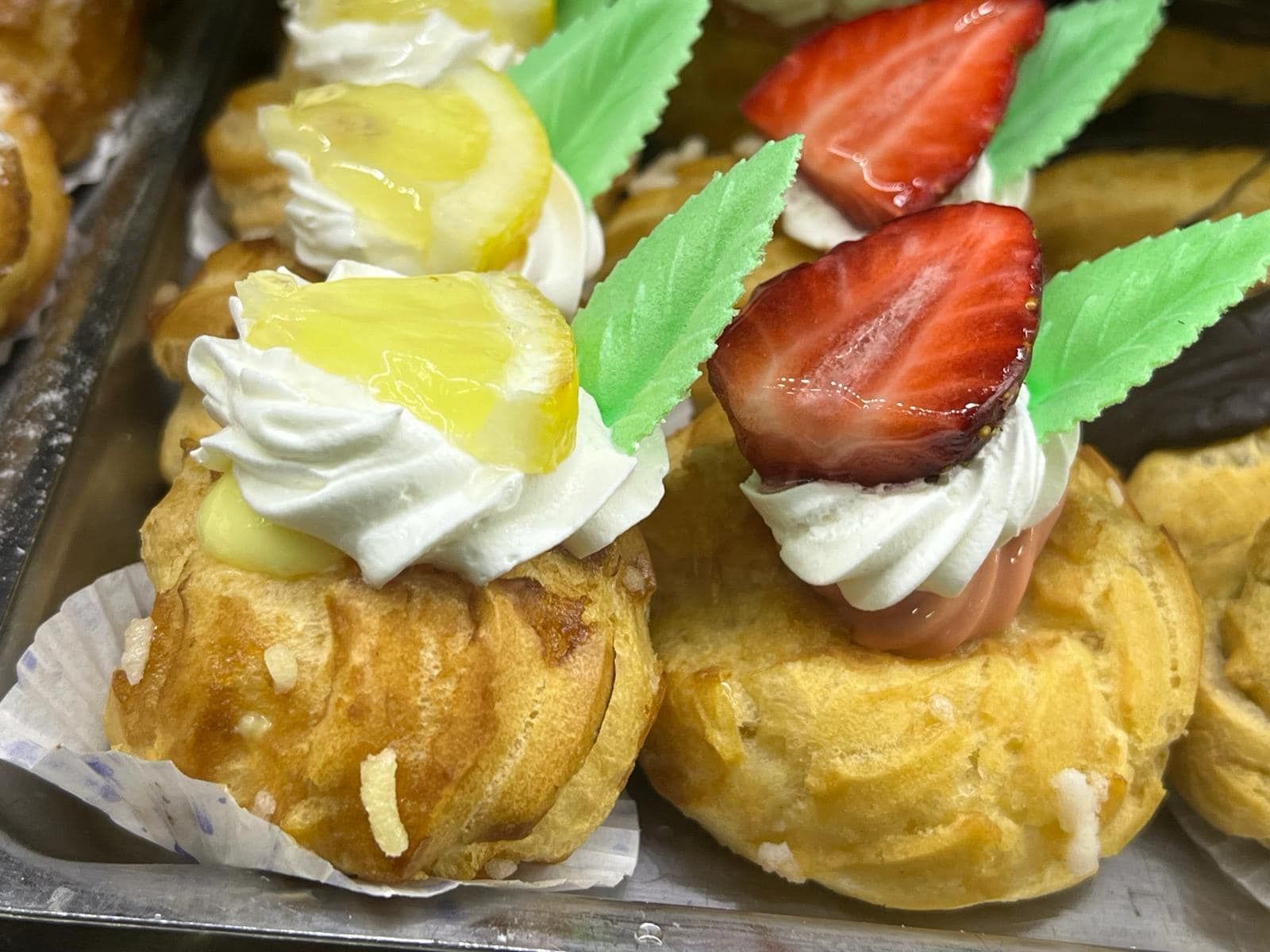 un vassoio di pasticcini con sopra panna montata e fragole