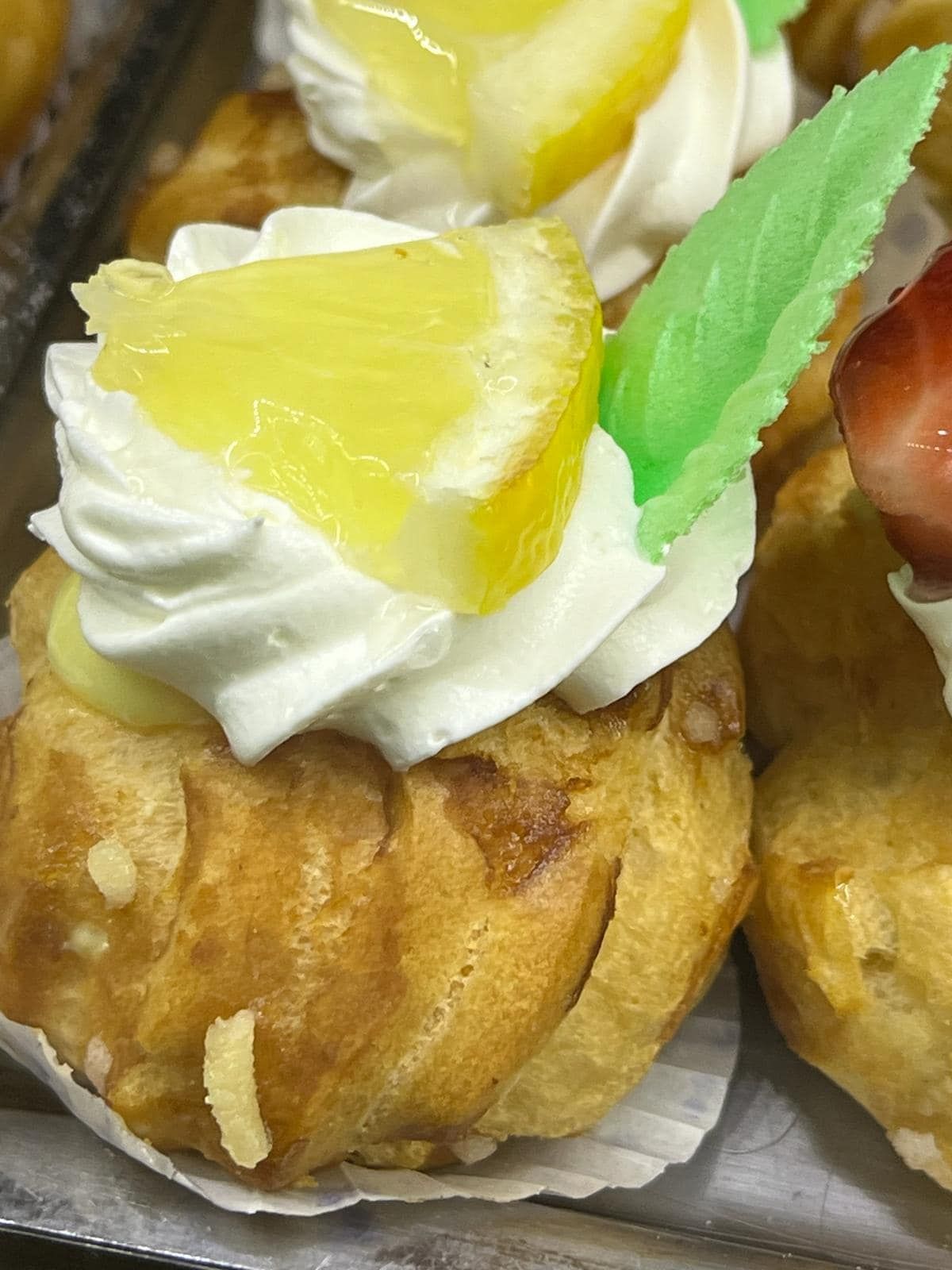 un primo piano di una pasta frolla con panna montata e una fetta di limone sopra.