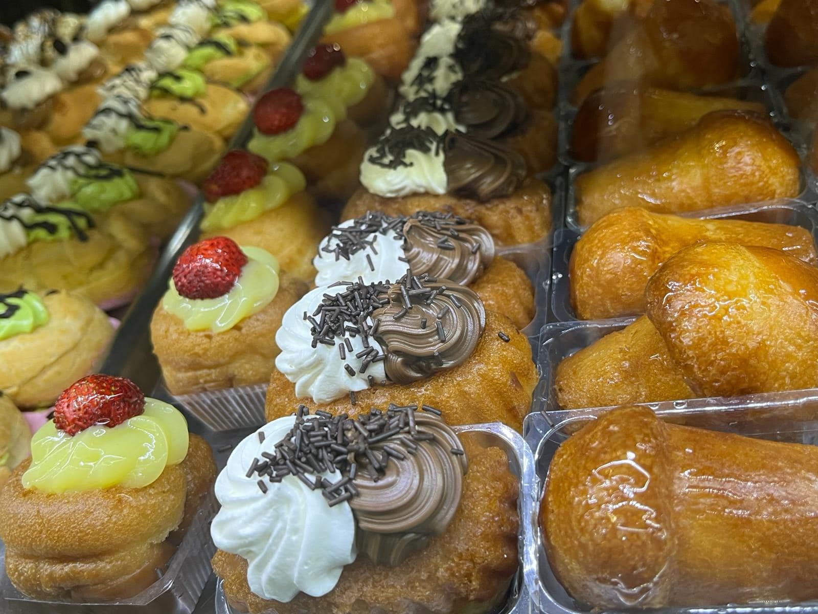 una varietà di dessert è esposta in contenitori di plastica.