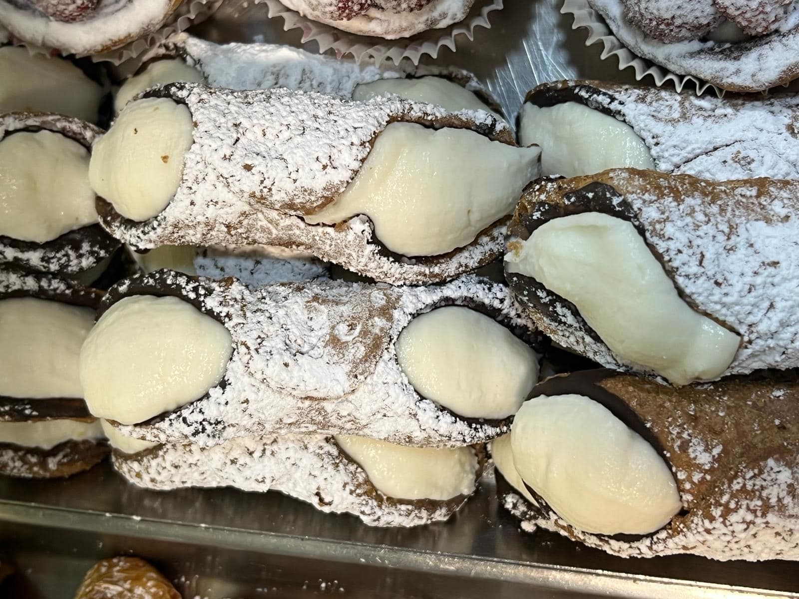 un vassoio di cannoli con sopra lo zucchero a velo