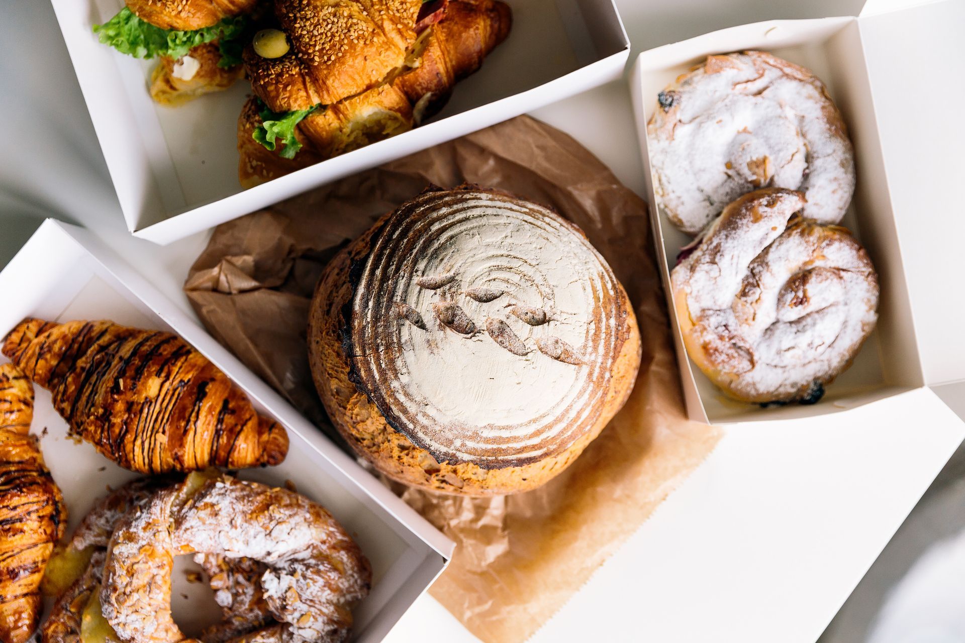 una varietà di pasticcini e panini in scatole su un tavolo.