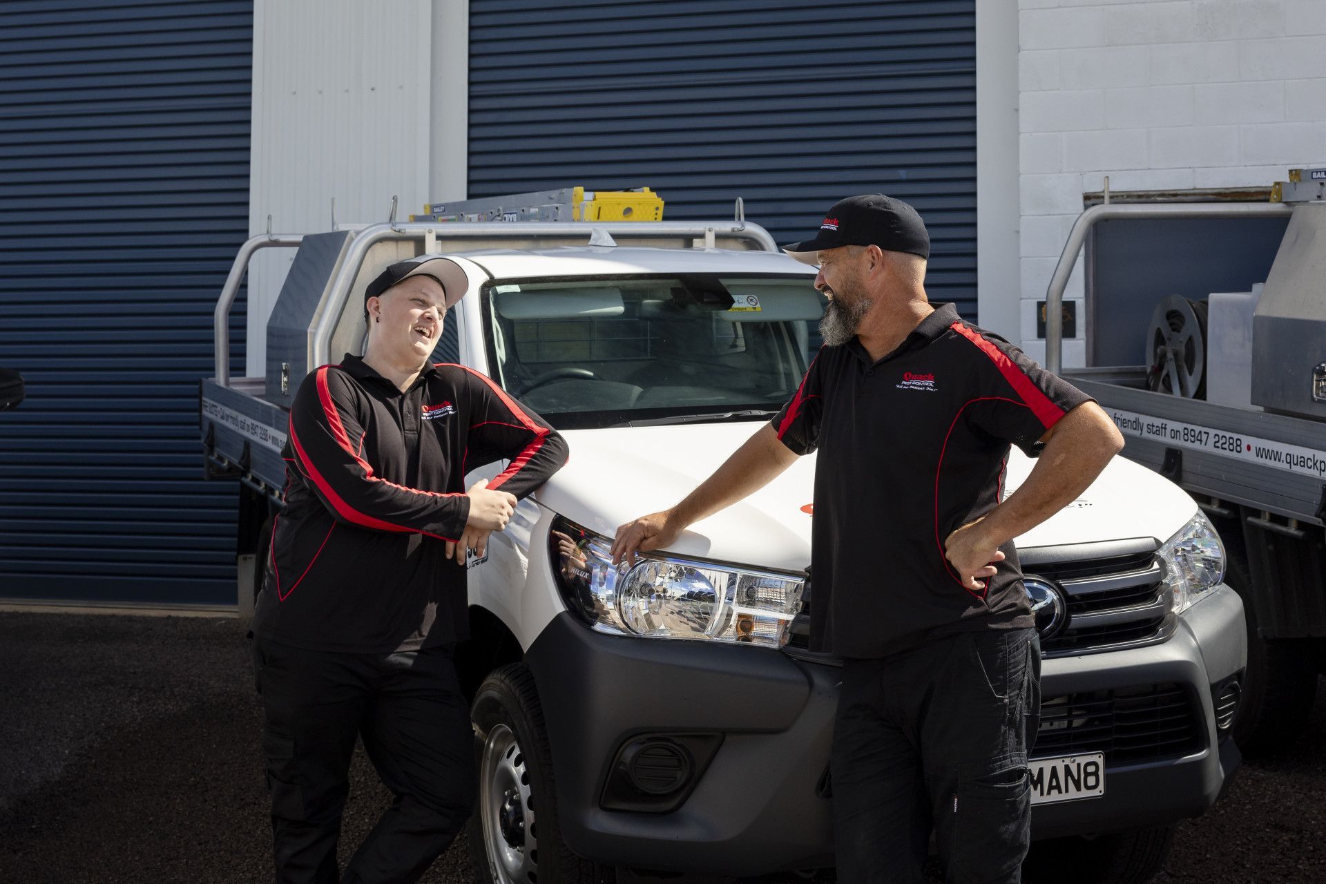 Two Men Unwinding Pipe — Quack Pest Control in Winnellie, NT