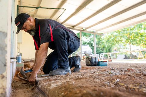 A Man Laying Down Bate on Dirt  — Quack Pest Control in Winnellie, NT