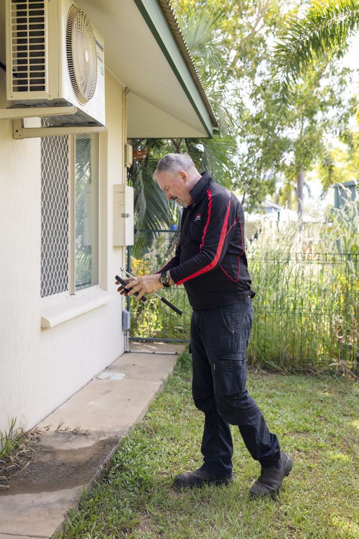 A Man Taking Image of The Side of The House— Quack Pest Control in Winnellie, NT