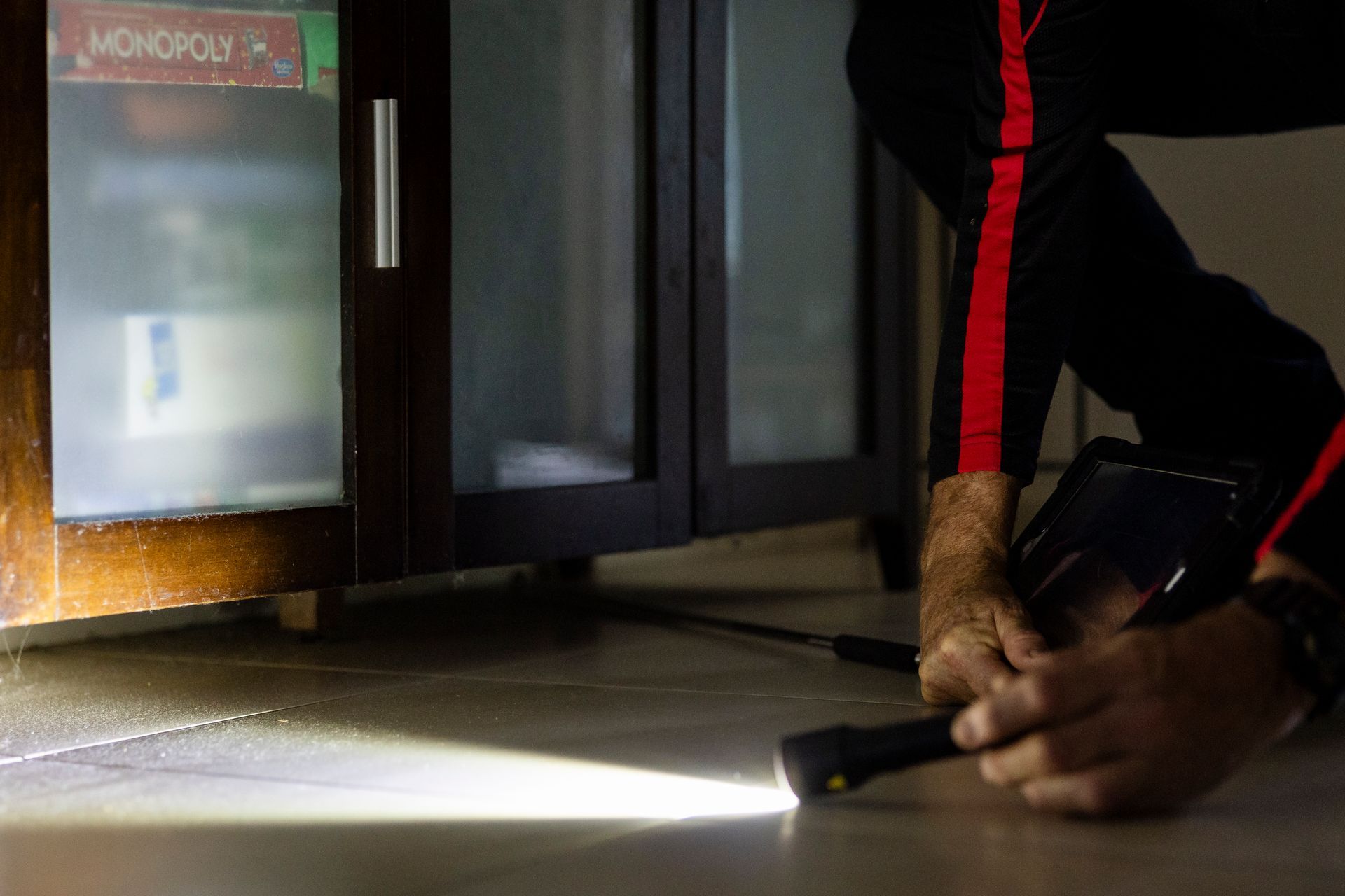 A Man Looking Under Cabinet with Torch — Quack Pest Control in Winnellie, NT