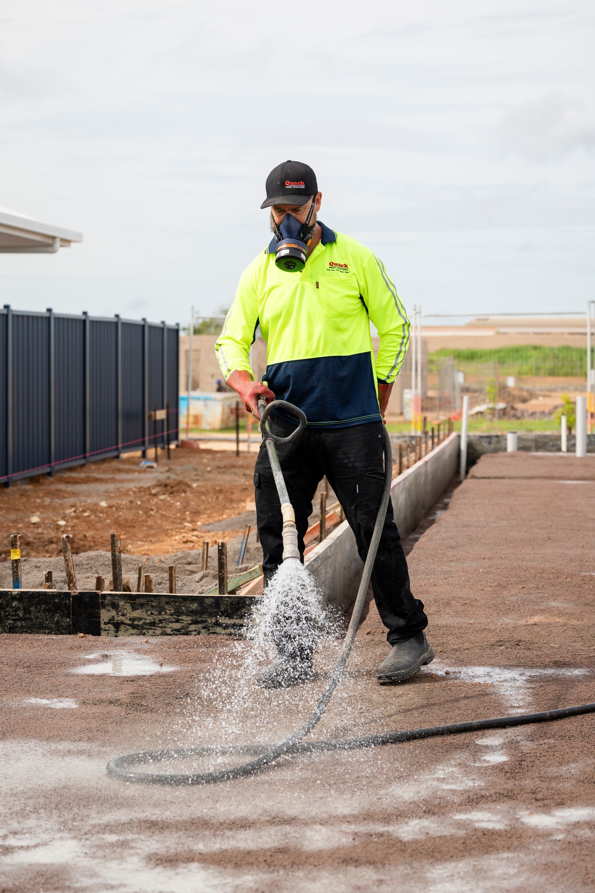 Construction Worker Spraying Concrete, Wearing Respirator and High-Vis Shirt — Quack Pest Control in Parap, NT