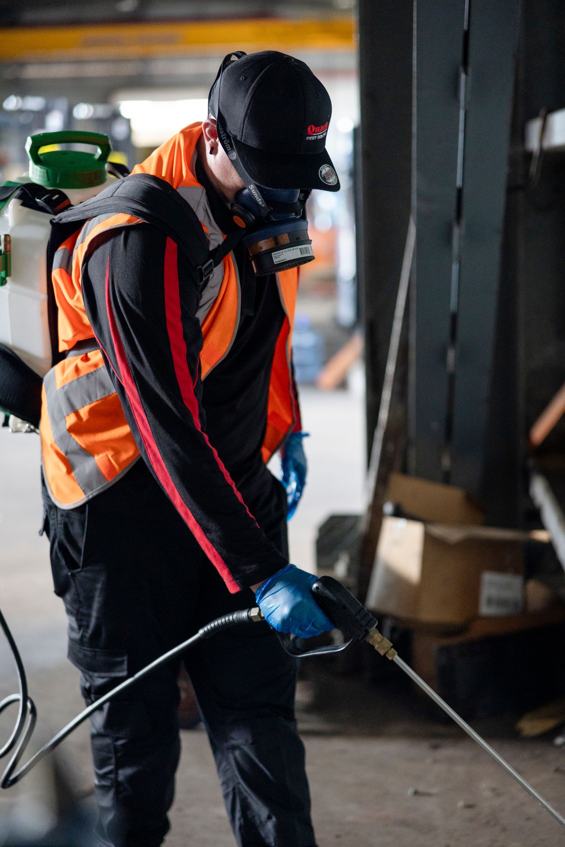 A Man is Spraying a Garage With a Sprayer — Quack Pest Control in Winnellie, NT