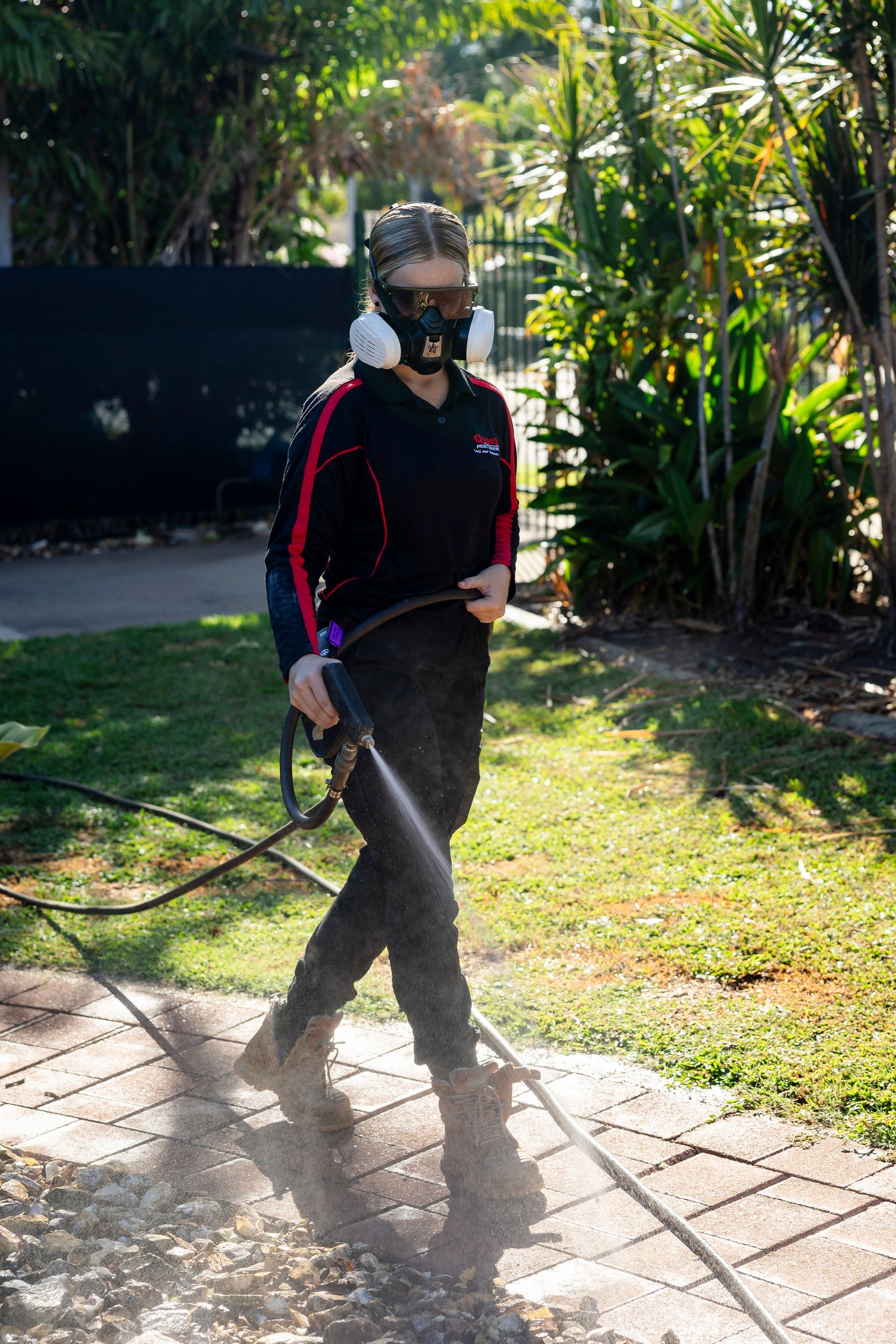 A Girl Spraying Path With Solution At Front Of House — Quack Pest Control in Winnellie, NT