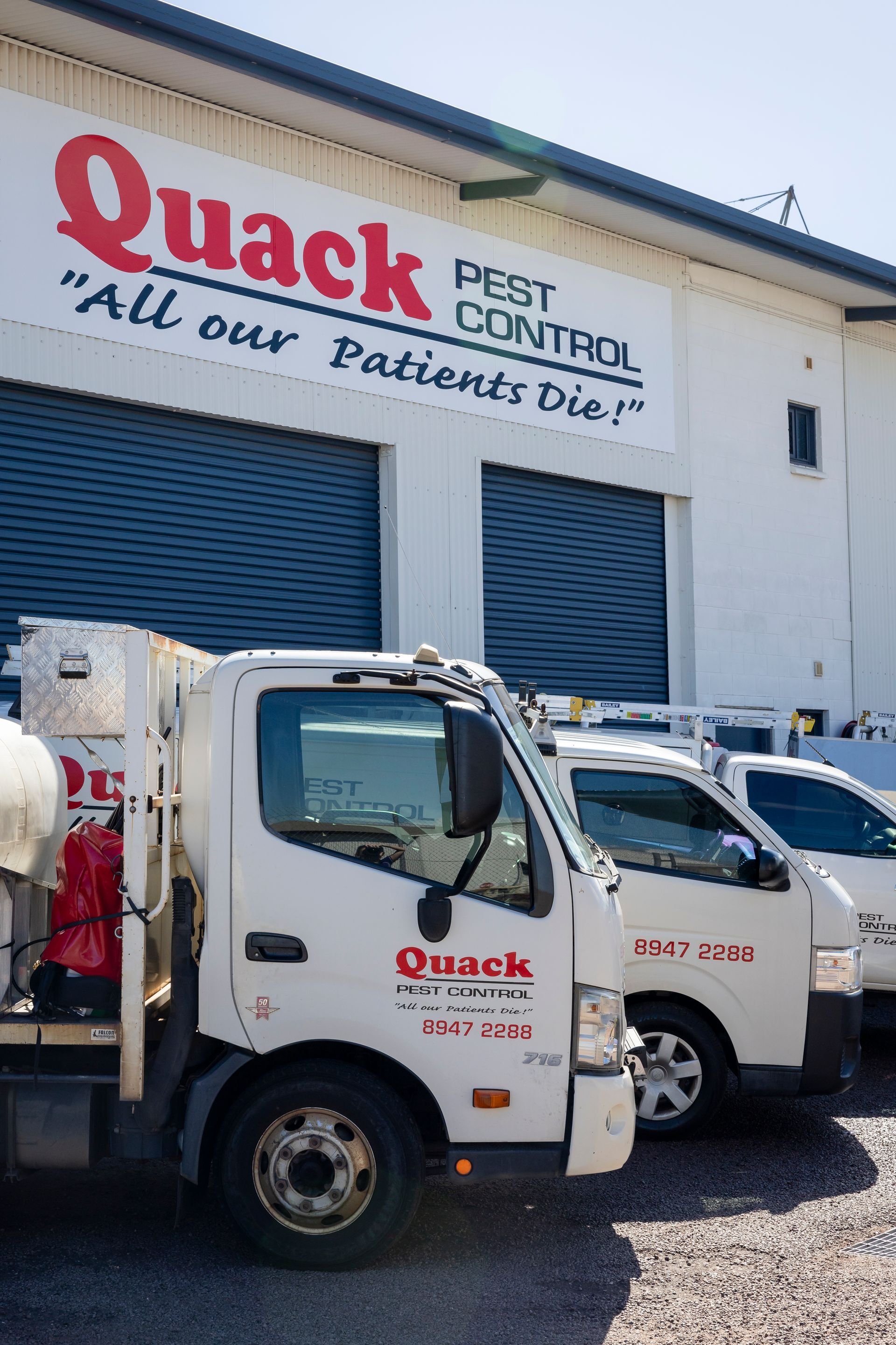 Three White Trucks Parked Outside Garage — Quack Pest Control in Winnellie, NT