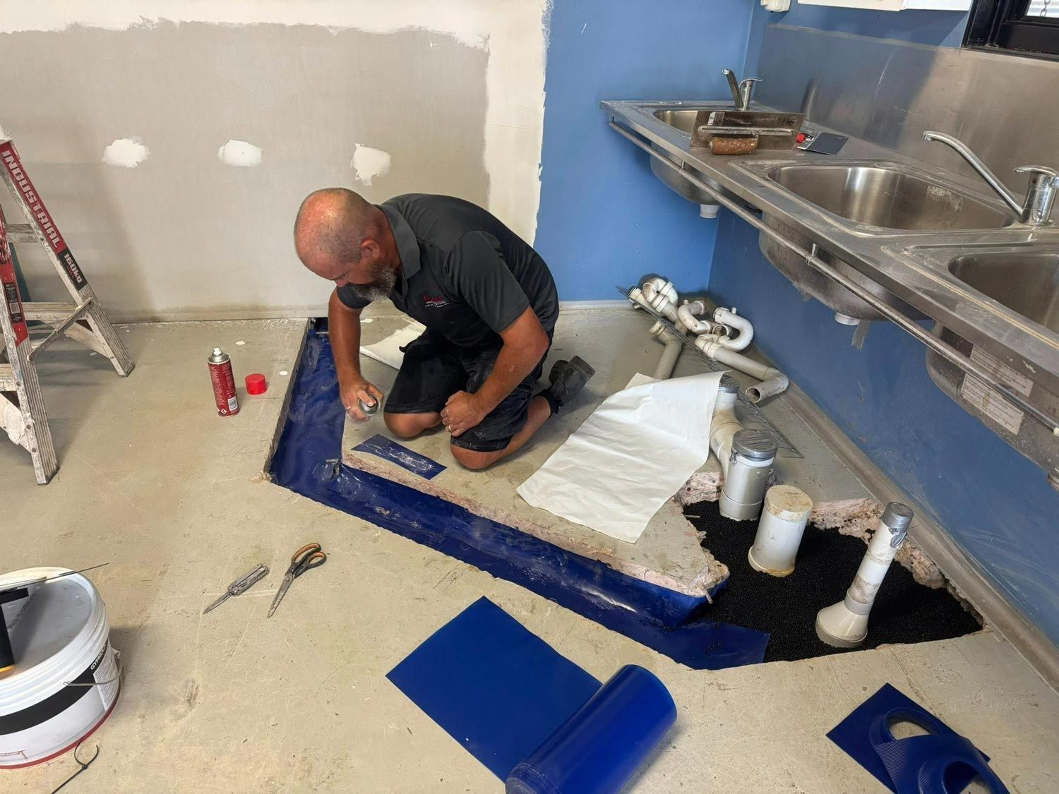 Technician applying termite treatment under a building floor