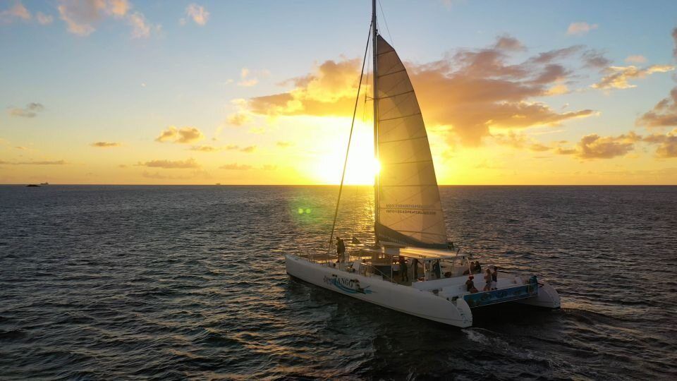A sailboat is sailing in the ocean at sunset.