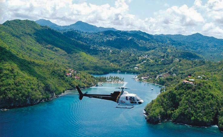 A helicopter is flying over a body of water surrounded by mountains.