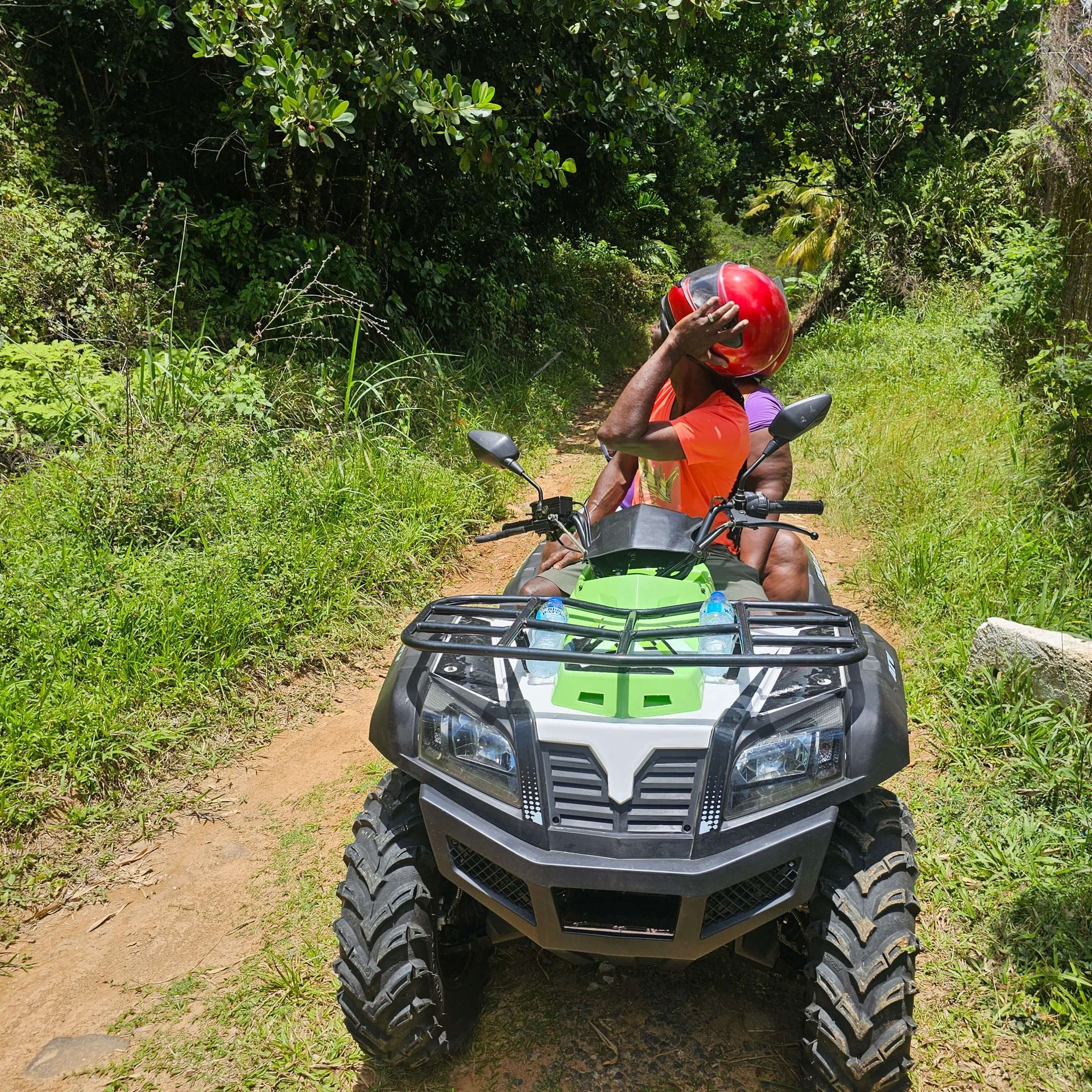 A man and a child are riding an atv on a dirt road.