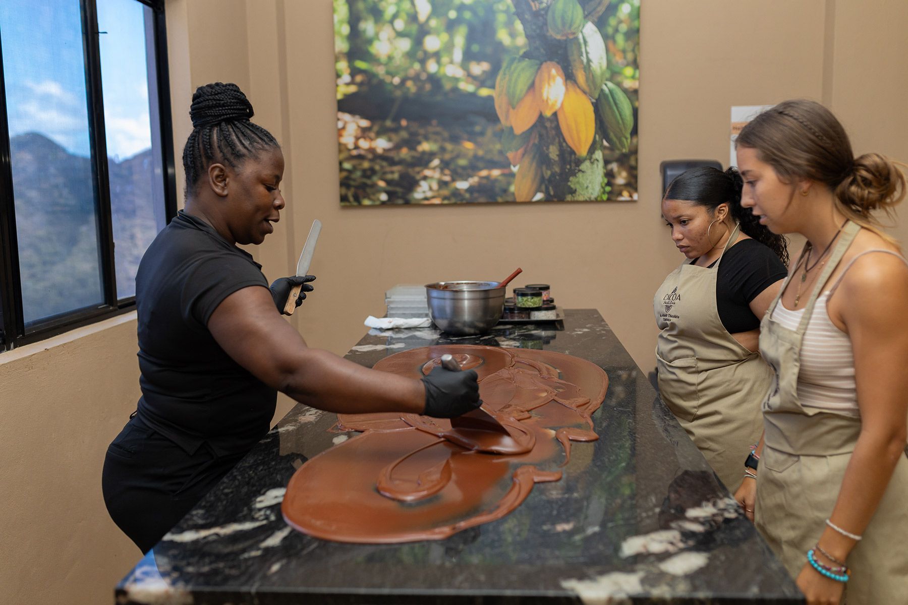 A group of women are standing around a table making chocolate.