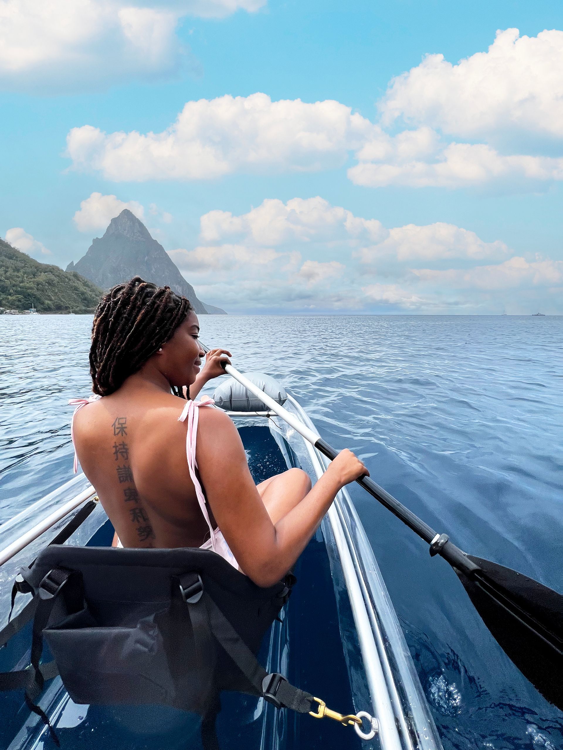 A woman is paddling a clear kayak in the ocean.