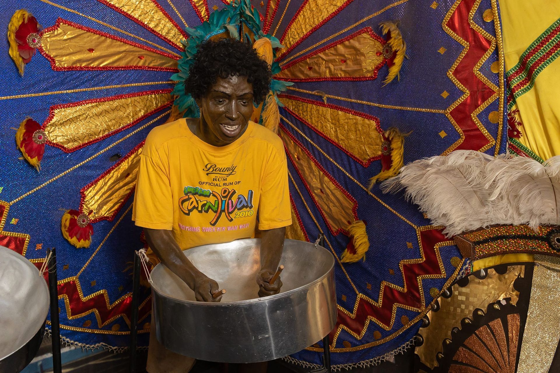 A man in a yellow shirt is playing a drum
