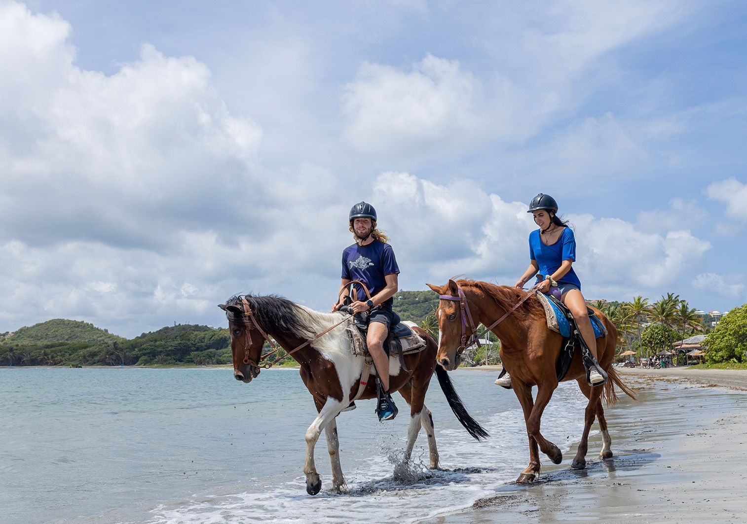 Two people are riding horses on the beach.