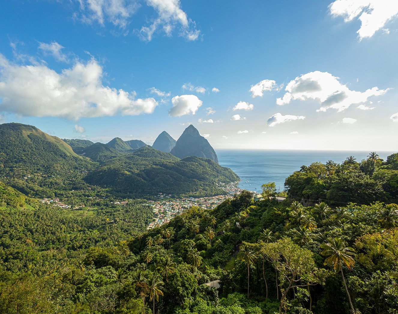 A view of a tropical landscape with mountains , trees , and the ocean.