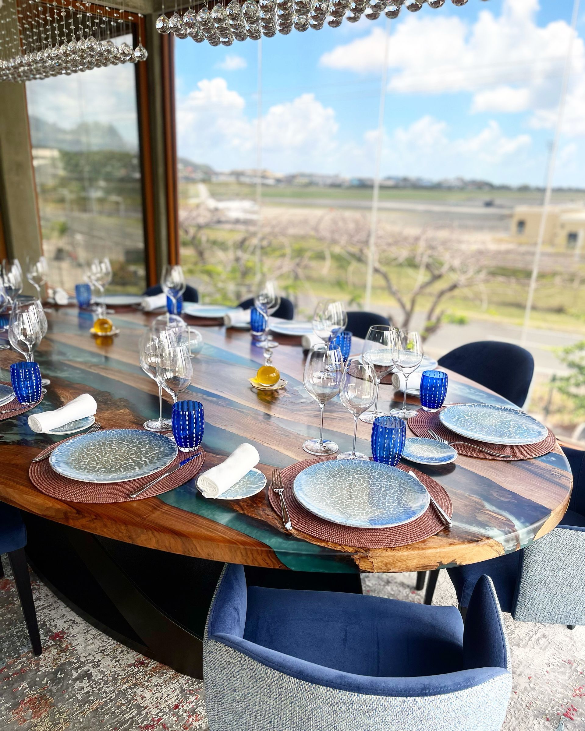 A dining room table with plates , glasses , and chairs.