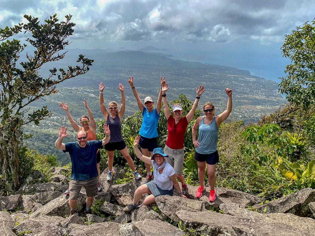 A group of people are posing for a picture on top of a mountain.