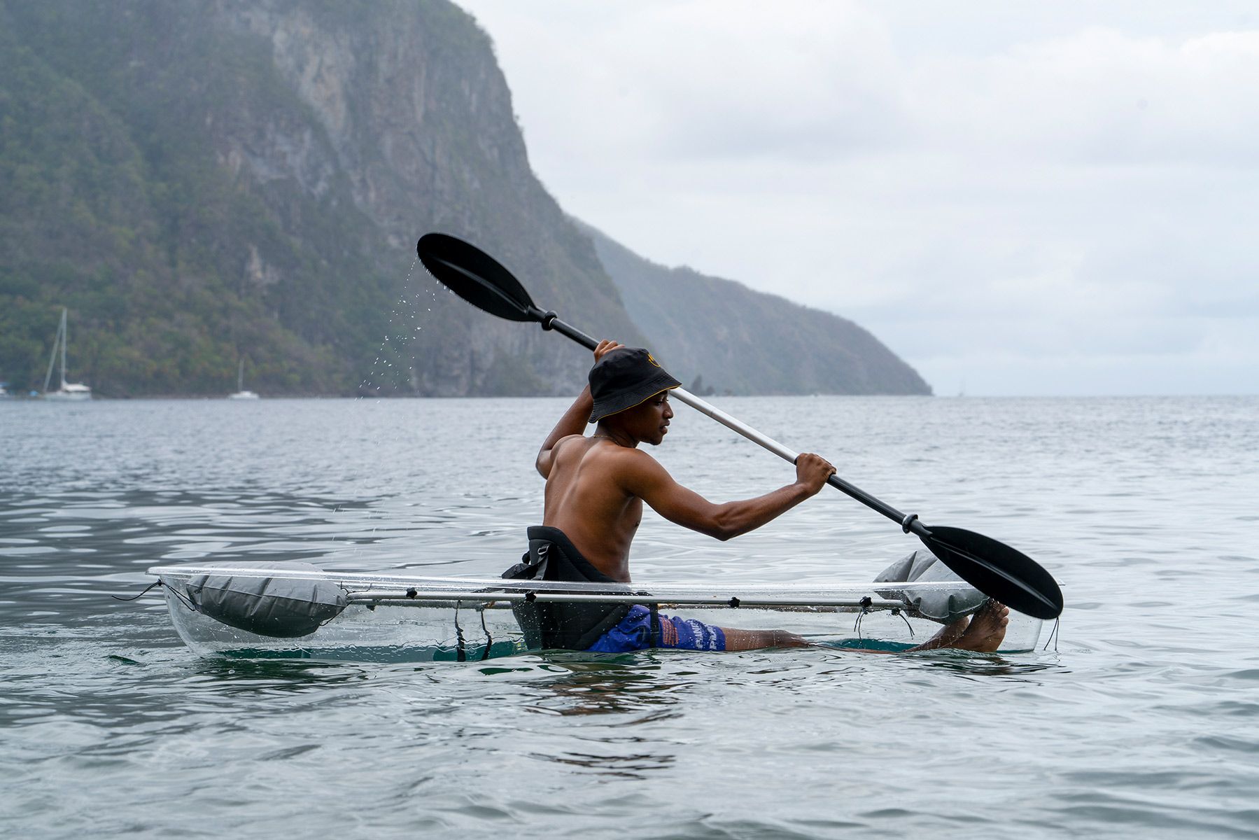 A man is paddling a clear kayak in the ocean.