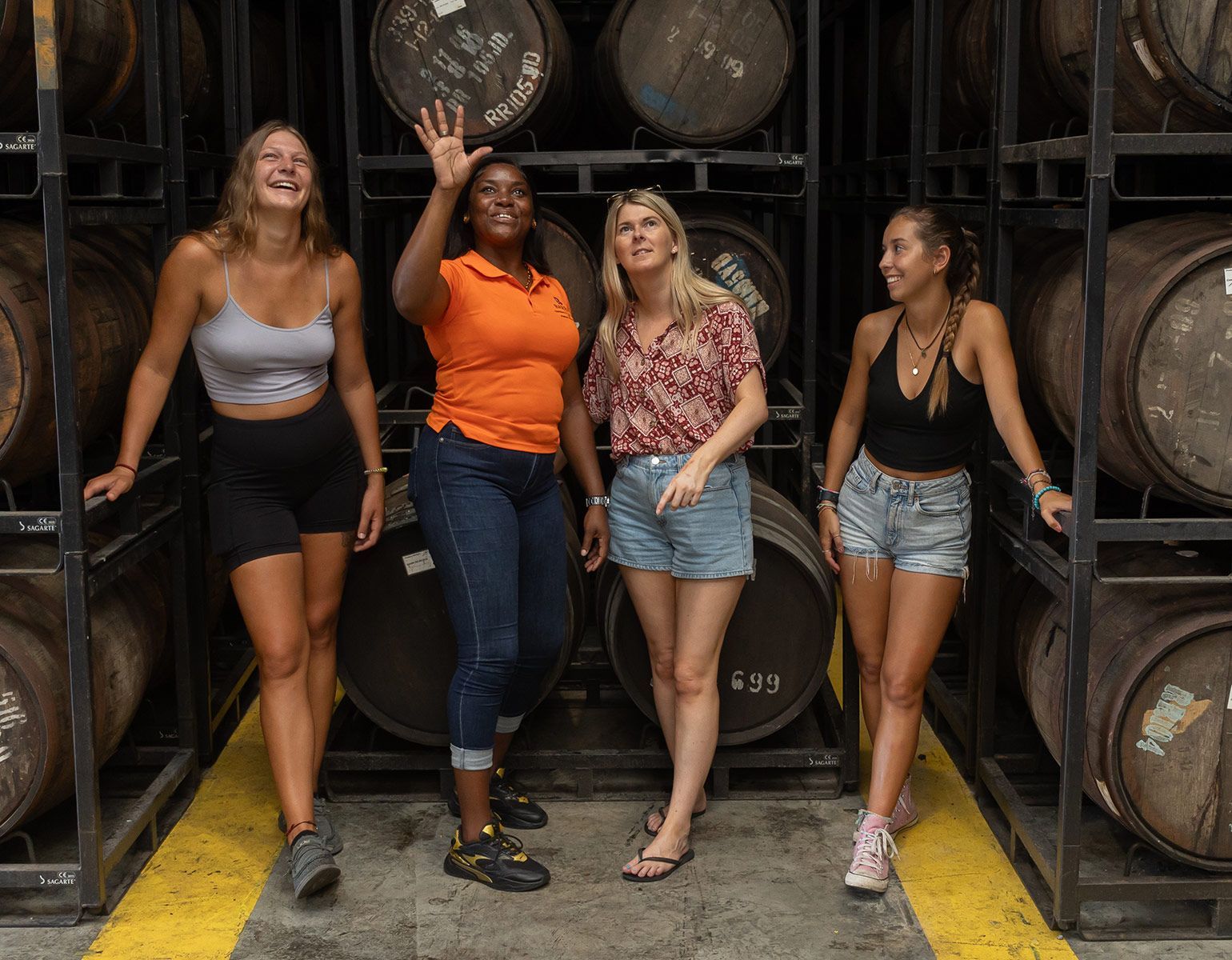 A group of women are posing for a picture in front of barrels.