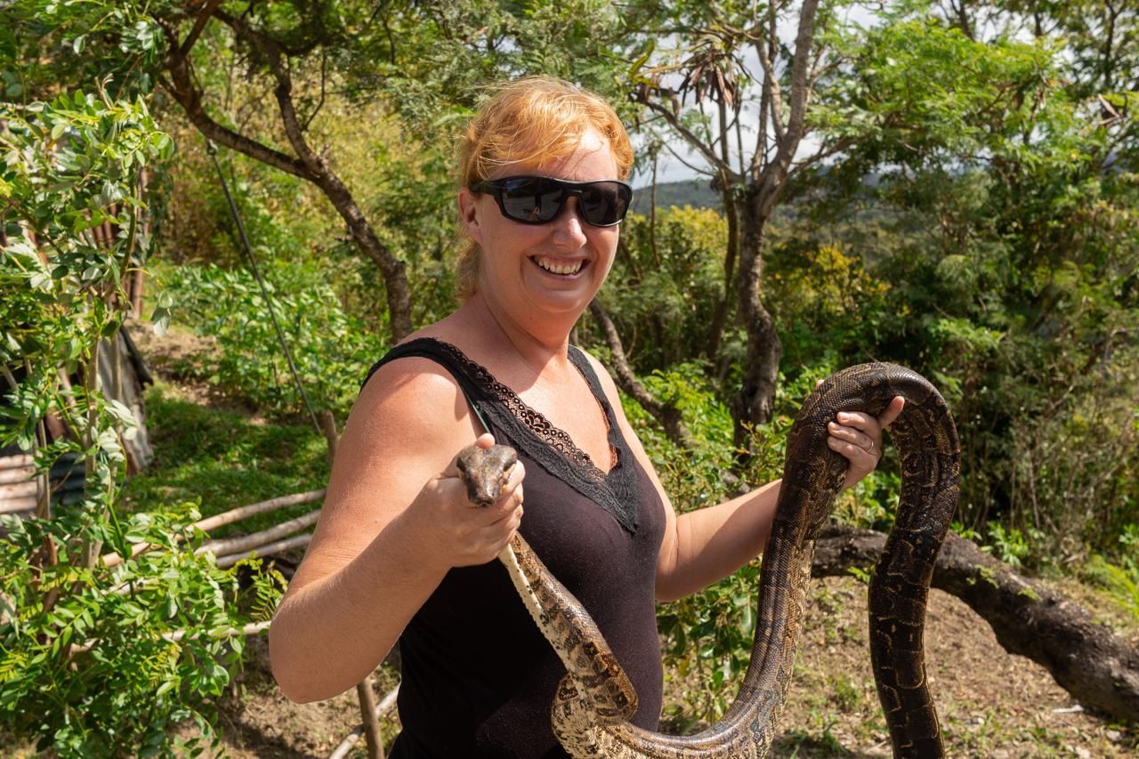 A woman is holding a large snake in her hands.