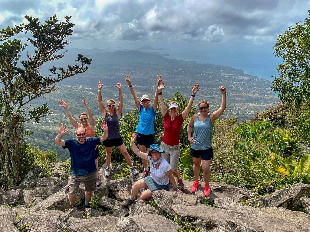 A group of people are posing for a picture on top of a mountain.