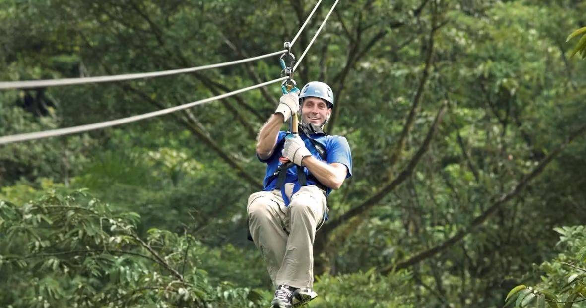 A man is flying through the air on a zip line.