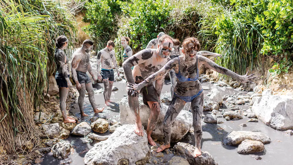 A group of people are standing on rocks covered in mud.