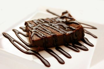 A brownie with chocolate sauce on a white plate