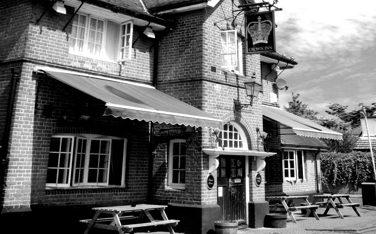 A black and white photo of a brick building with picnic tables outside