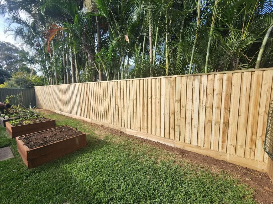 A Wooden Fence Surrounds a Garden in A Backyard — Byron & Beyond Fencing In Billinudgel, NSW 