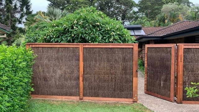 A Wooden Fence Surrounds a Driveway Leading to A House — Byron & Beyond Fencing In Billinudgel, NSW