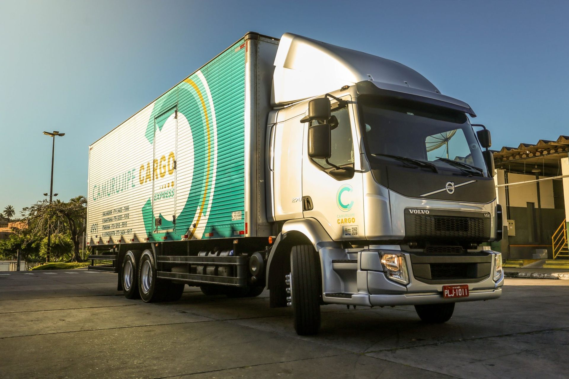 Uma casa no meio de uma floresta com montanhas ao fundo.