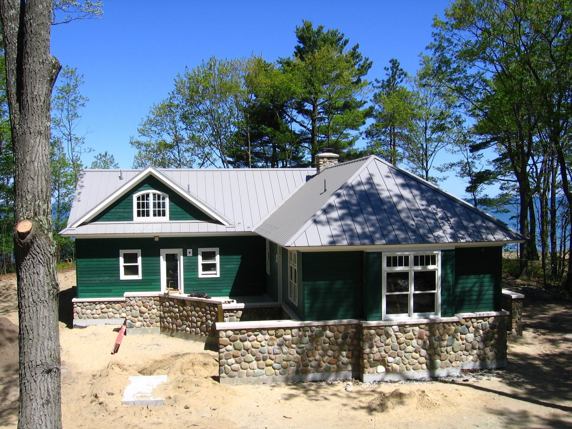 A green house with a gray roof and white windows