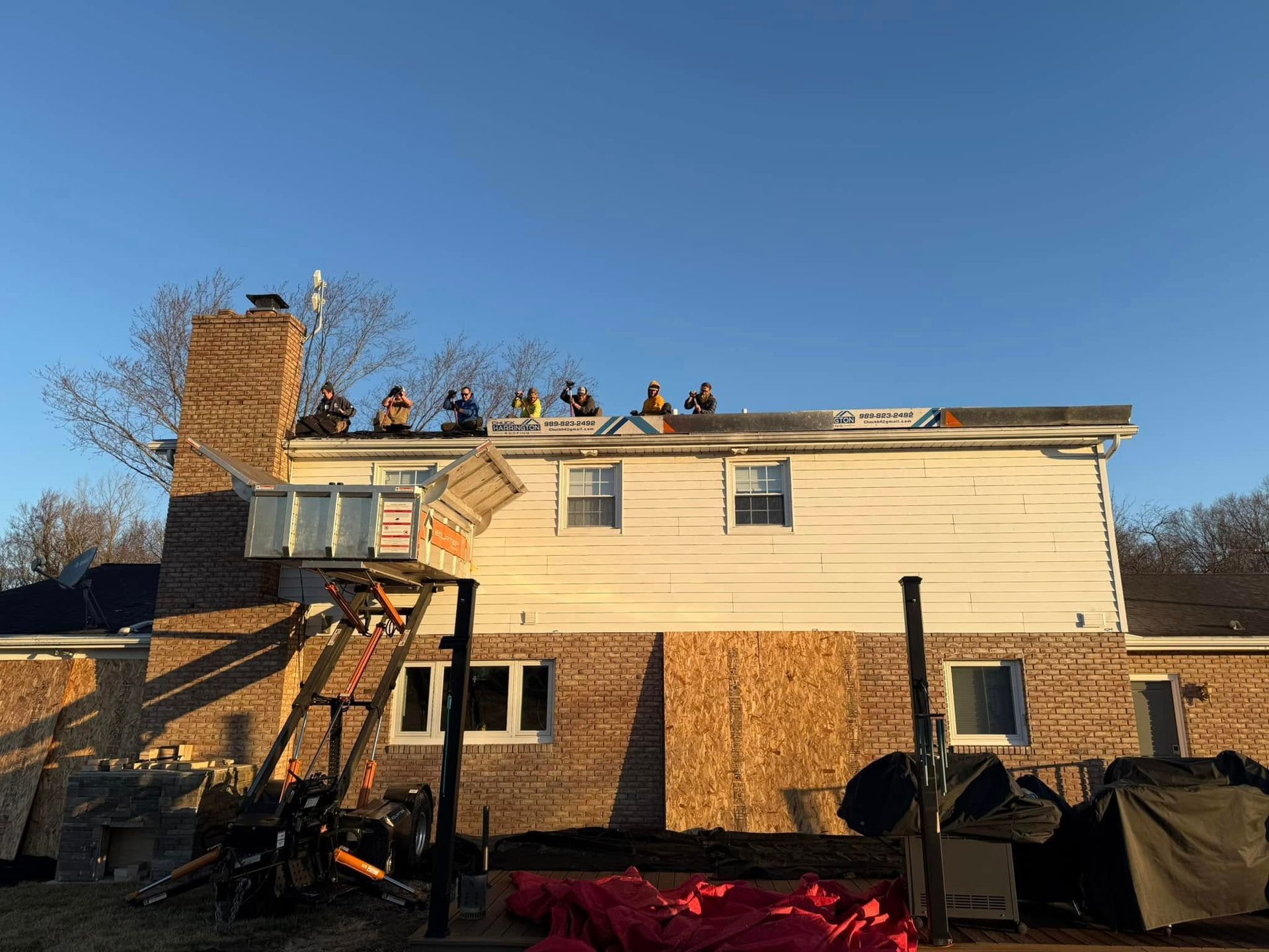 A group of people are working on the roof of a house.