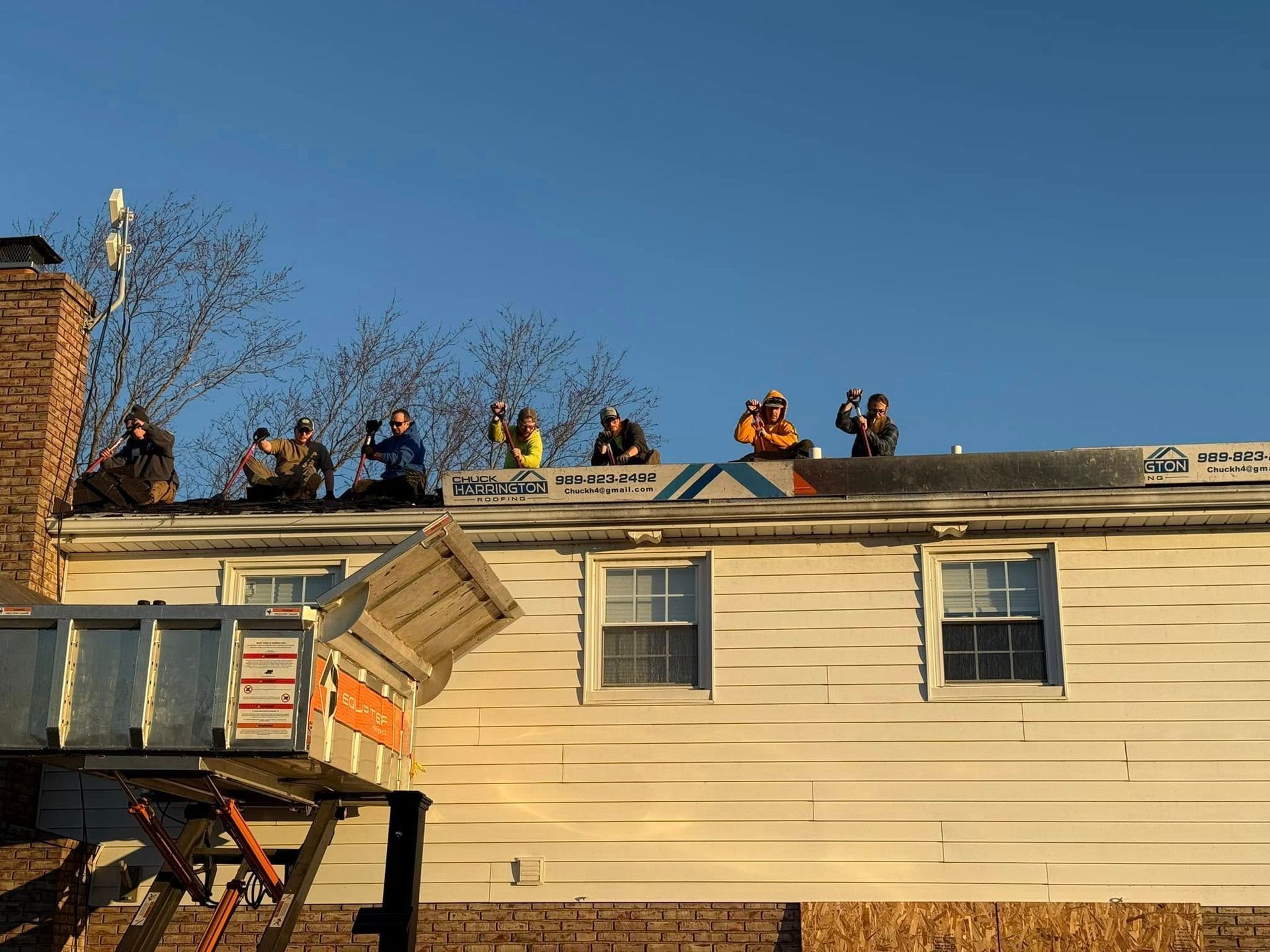 A group of people are sitting on the roof of a house.